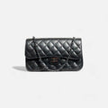 Bolso acolchado de piel negra con cadena metálica oscura y diseño en diamante elegante y moderno
