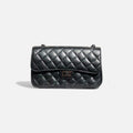 Bolso acolchado negro con cadena metálica oscura y diseño moderno elegante