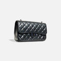 Bolso acolchado negro con cadena metálica oscura y diseño sofisticado en forma de diamante